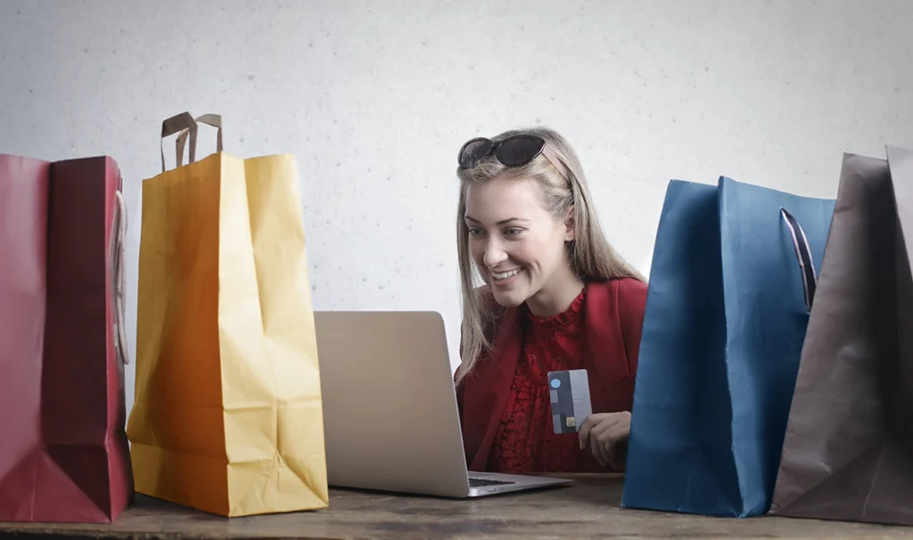 Winkeltassen staan op een tafel met daar tussen een vrouw die een laptop voor zich heeft.