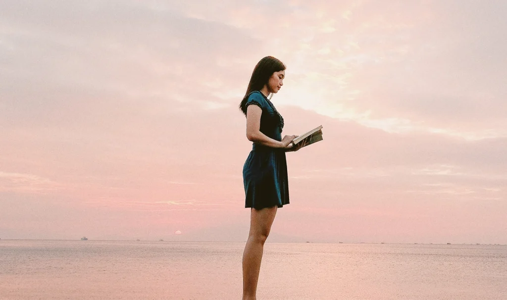 Een vrouw leest een boek terwijl ze omringd is door natuur.