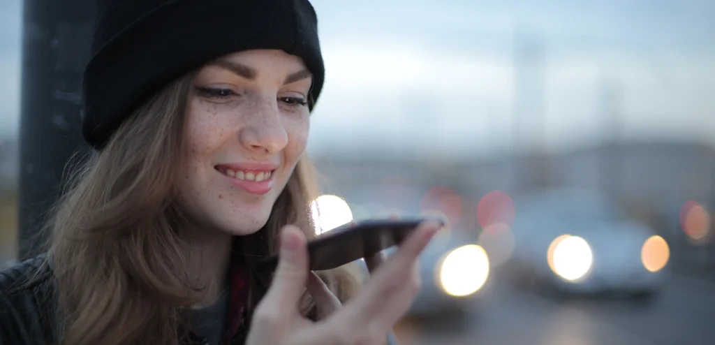 en vrouw met een beanie kijkt naar haar smartphone terwijl ze deze vasthoudt
