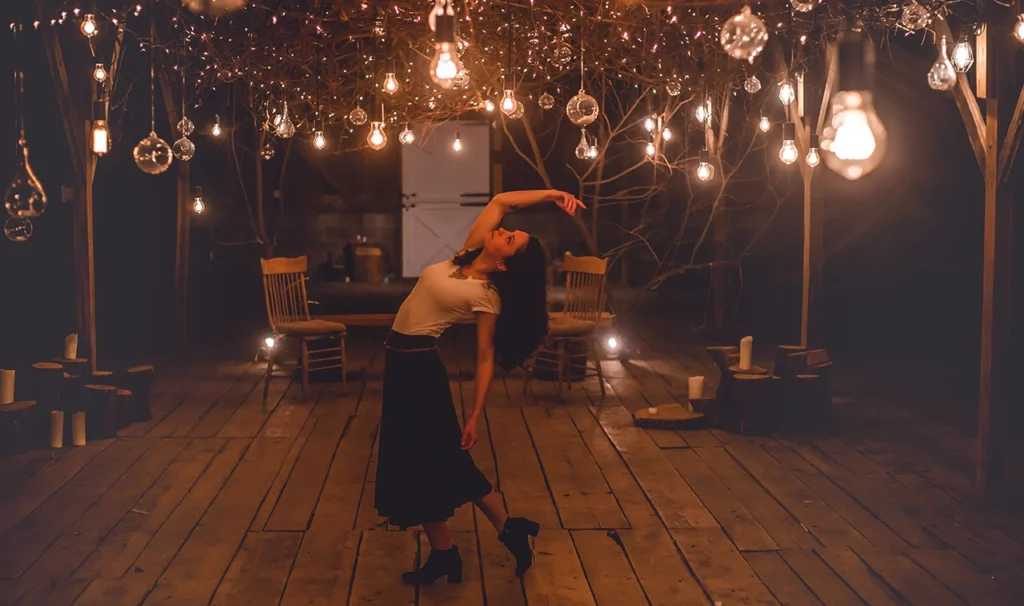 Een vrouw danst in een verlichte kamer, omringd door kleurrijke lichten en een levendige sfeer.