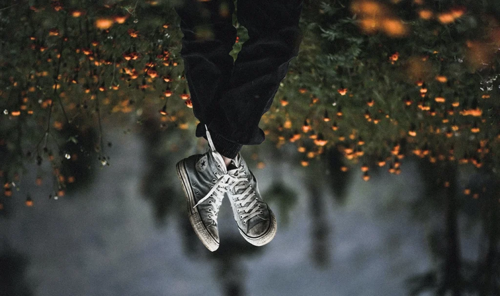 Een paar sneakers zijn zichtbaar terwijl de voeten in de lucht hangen.